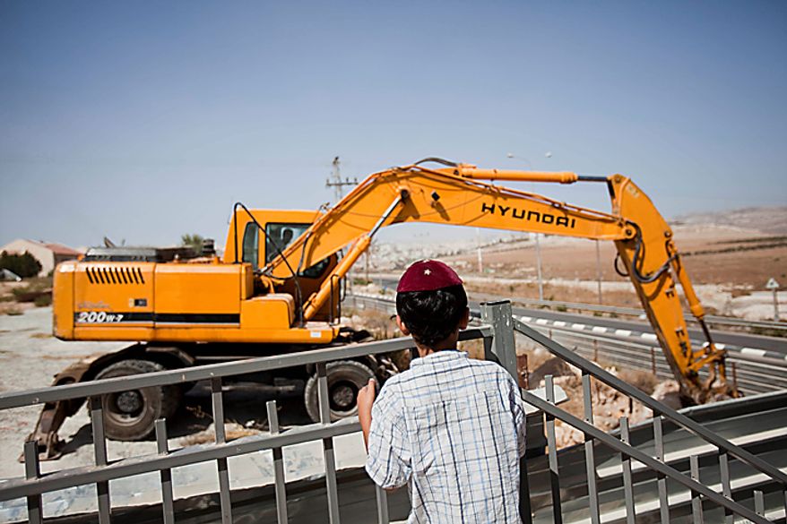 ** FILE ** A Jewish settler boy looks at earth-moving equipment working at a construction site in the West Bank Jewish settlement of Adam, near Ramallah, on Monday, Sept. 27, 2010. (AP Photo/Bernat Armangue)