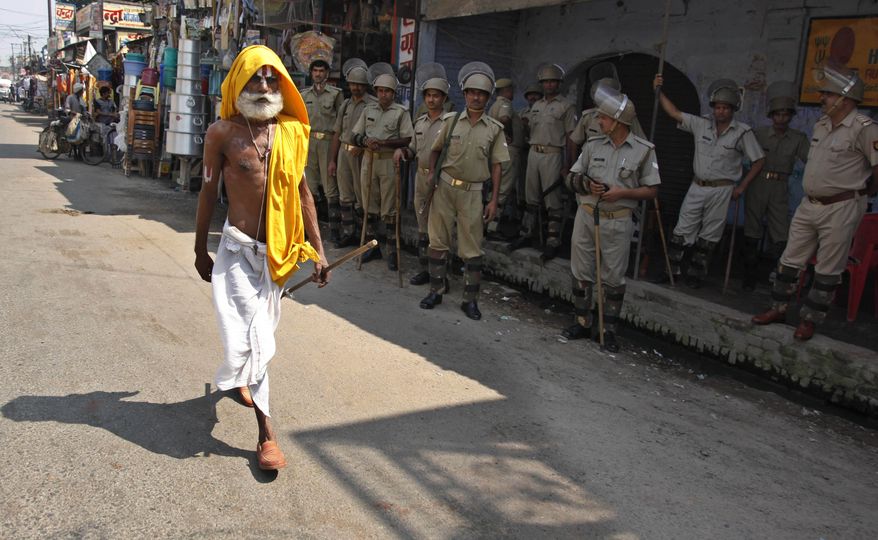 A Hindu holyman walks past Indian securitymen standing guard in Ayodhya, India, Tuesday, Sept. 28, 2010. The Indian Supreme Court rejected Tuesday a plea to delay judgment on whether Hindus or Muslims should control a disputed holy site, clearing the way for a verdict in the explosive case later this week. (AP Photo/Rajesh Kumar Singh)