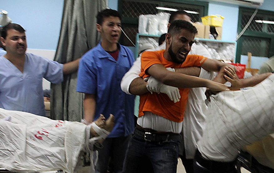 Palestinians react over one of three dead bodies of Islamic Jihad militants at the treatment room of Al-Aqsa hospital in Deir el-Balah, central Gaza Strip, Tuesday, Sept. 28, 2010. The three Palestinian militants were killed late Monday in a clash with Israeli soldiers, both sides said. The Israelis said their forces fired at militants near the border of central Gaza as they were about to launch rockets at Israel. (AP Photo/Ashraf Amra)