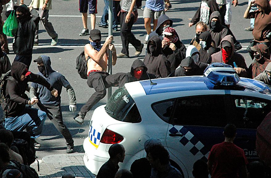 Protesters vandalize a police car during riots in Barcelona on Wednesday, Sept. 29, 2010. Shortly after, the car was set on fire. Spanish workers staged a general strike Wednesday to protest austerity measures imposed by a government struggling to slash its budget deficit and overcome recession. (AP Photo/Paula Fernandez)