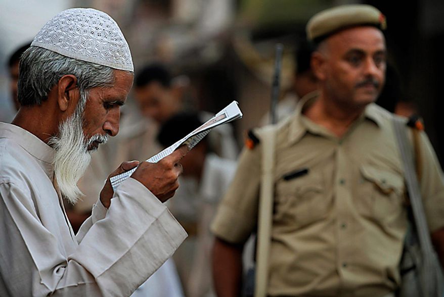 An Indian Muslim reads a newspaper as a policeman patrols a street, ahead of the verdict on whether Hindus or Muslims should control a disputed holy site in Ayodhya, India, Thursday, Sept. 30, 2010. A 16th-century Babri Mosque in the town of Ayodhya was razed by Hindu hard-liners in 1992, setting off violence that killed 2,000 nationwide. Hindus say the mosque, built in 1528 by the Mughal emperor Babur, was erected at the birthplace of their god, Rama and want to build a temple to Rama there. (AP Photo/Rajesh Kumar Singh)