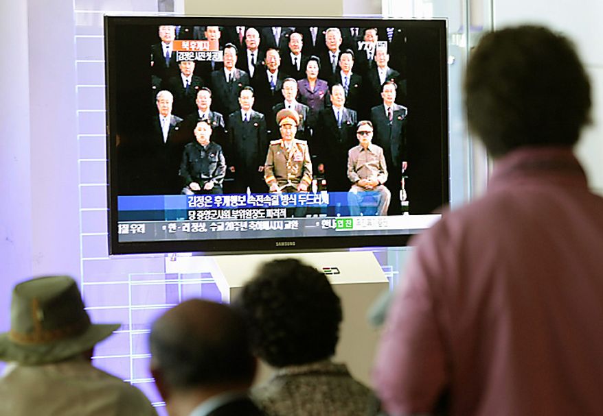 South Koreans watch a TV news program showing North Korean leader Kim Jong Il, right, posing for a group photo with newly elected members of the central leadership body of the Workers Party of Korea (WPK) including a man believed to be his third son Kim Jong Un, sitting at left of photo, and Vice Marshal Ri Yong Ho, sitting at center, as well as participants in the WPK Conference, in front of the Kumsusan Memorial Palace, in Pyongyang, North Korea, at the Seoul Railway Station in Seoul, South Korea, Thursday, Sept. 30, 2010. (AP Photo/Ahn Young-joon)