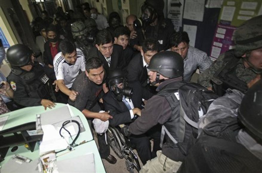 Ecuador's President Rafael Correa, sitting in a wheelchair and wearing a gas mask, is rescued from a hospital where he was holed up by protesting police in Quito, Ecuador, Thursday Sept. 30, 2010. The army rescued Correa from a hospital where he had been trapped by rebellious police for more than 12 hours while he was being treated for tear-gas fired by hundreds of police angry over a law that they claim would cut their benefits. (AP Photo/Dolores Ochoa)