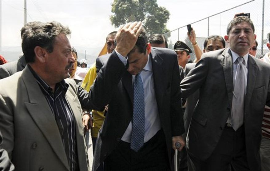 Ecuador's President Rafael Correa, center, covers his head as he runs away from tear gas during a protest of police officers and soldiers against a new law that cuts their benefits at a police base in Quito, Ecuador, Thursday, Sept. 30, 2010. There were no reports of serious violence against the government, but Correa was hospitalized due to the effects of tear gas after being shouted down and pelted with water as he tried to speak with a group of police protesters. (AP Photo/Patricio Realpe)
