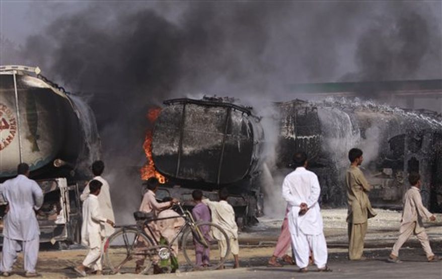 Pakistani residents walk by the still smoldering oil trucks in Shikarpur, southern Pakistan on Friday Oct. 1, 2010. Suspected militants set ablaze at least 27 tankers carrying fuel for U.S. and NATO troops in Afghanistan on Friday, police said. (AP Photo/Aaron Favila)
