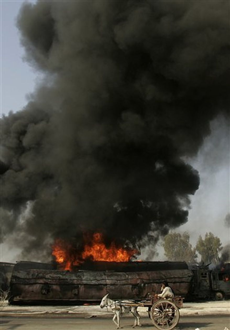 A Pakistani man on a donkey-drawn cart passes by a burning oil trucks in Shikarpur, southern Pakistan on Friday Oct. 1, 2010. Suspected militants set ablaze at least 27 tankers carrying fuel for U.S. and NATO troops in Afghanistan on Friday, police said. (AP Photo/Aaron Favila)