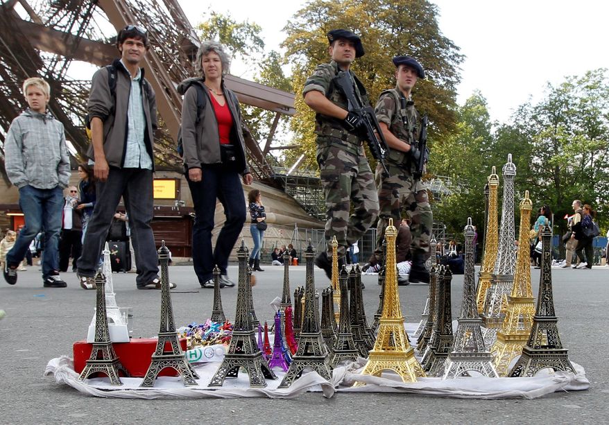 TOWERING THREAT: French soldiers patrol the Eiffel Tower in Paris on Sunday. The State Department is cautioning Americans traveling in Europe to be vigilant because of heightened concerns about a terrorist attack, but the U.S. has not told citizens to forgo travel to Europe. (Associated Press)