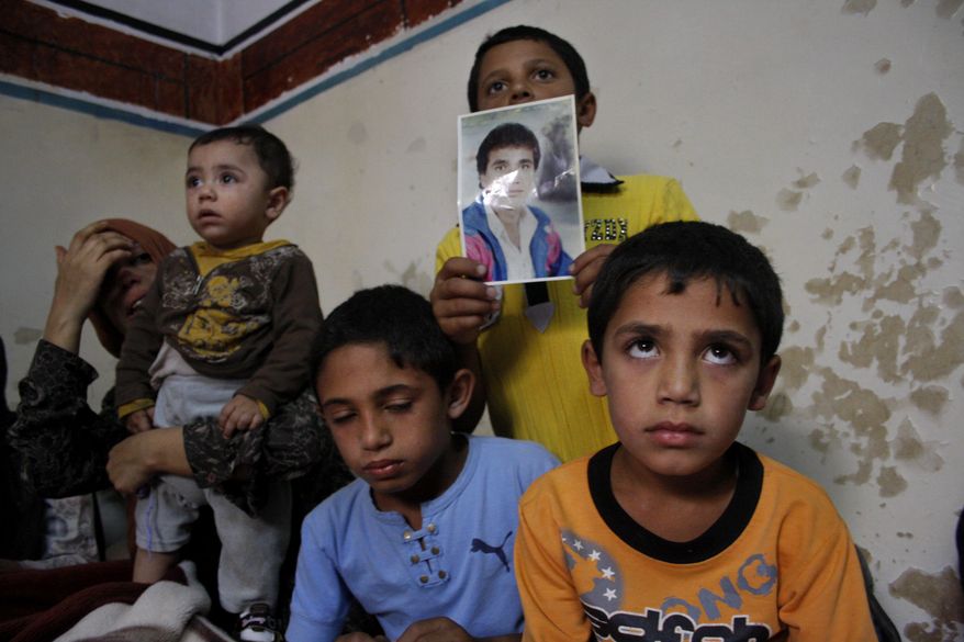 Fathiya Qawasmeh (left), the wife of 37-year-old Izzedine Qawasmeh, seen in the portrait held by one of his sons, is surrounded by her children as she mourns the death of her husband in the village of Sair, near the West Bank city of Hebron, on Sunday, Oct. 3, 2010. Mr. Qawasmeh, a construction worker, was shot and killed by Israeli police early Sunday after using a rope to climb over a towering cement wall meant to keep Palestinians without entry permits out of Israel, police and a witness said. (AP Photo)