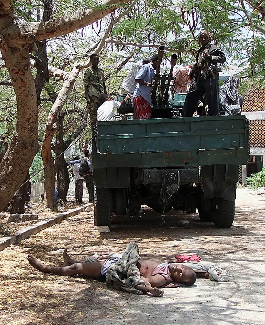 Al-Shabab militants stand of the back of a truck with an anti aircraft gun mounted on the back near the body of Somali government soldier who was killed during clashes with Islamists in southern Mogadishu's Hodon neighborhood , Somalia, Monday Oct.4, 2010. Ali Muse, the head of Mogadishu's ambulance service, says a spike in violence the last three days in Mogadishu has killed at least 20 civilians. More than 70 people have been wounded.(AP Photo/Farah Abdi Warsameh)