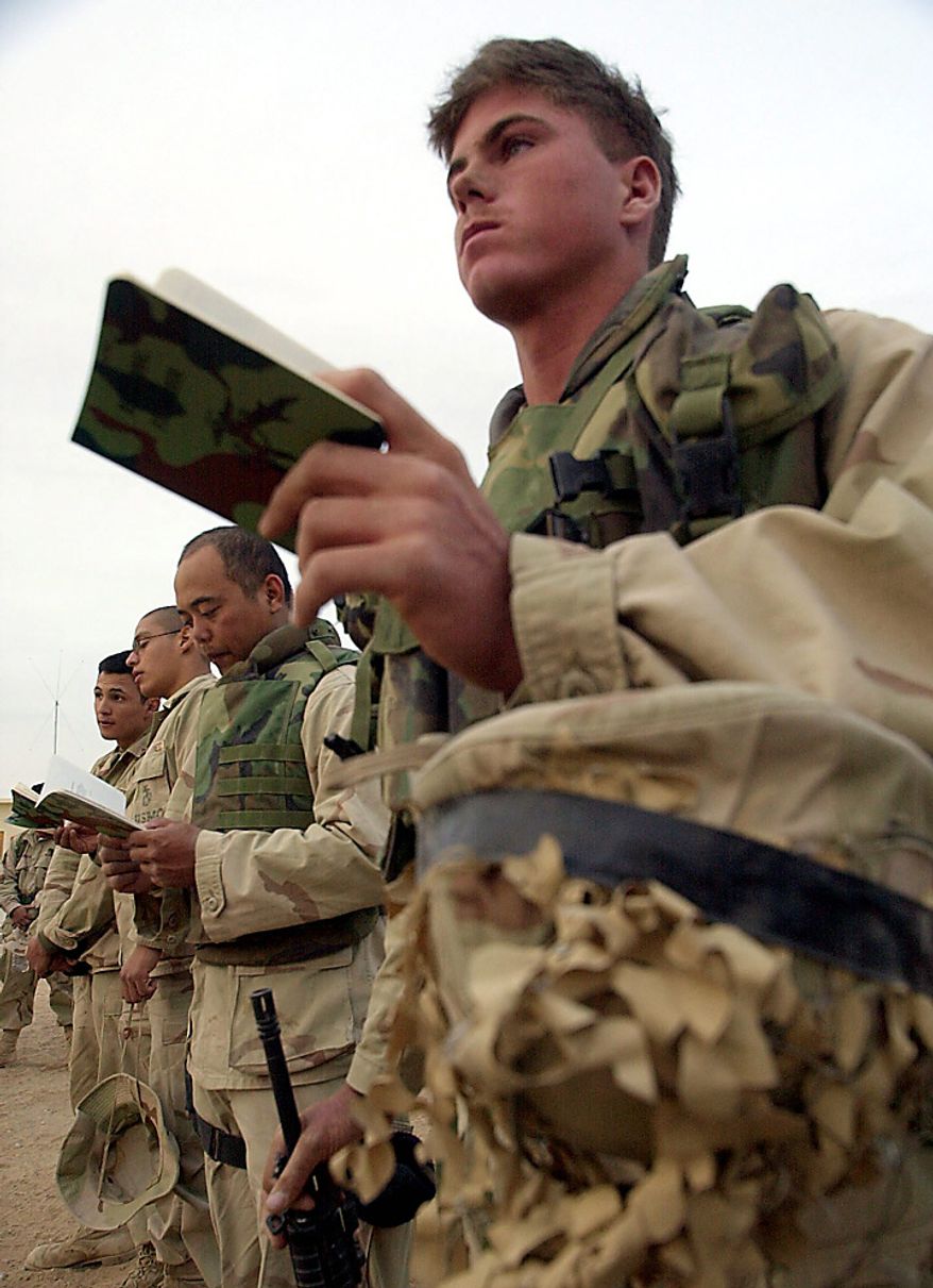 In this Wednesday, Dec. 12, 2001 file picture, Marine Lance Cpl. Chris McNeely, right, of Whiting, Kan., holds his battlefield hymnal as he attends a memorial service at Camp Rhino in southern Afghanistan, to commemorate the three-month anniversary of the Sept. 11 terrorist attacks in the United States. (AP Photo/Dave Martin, Pool, File)