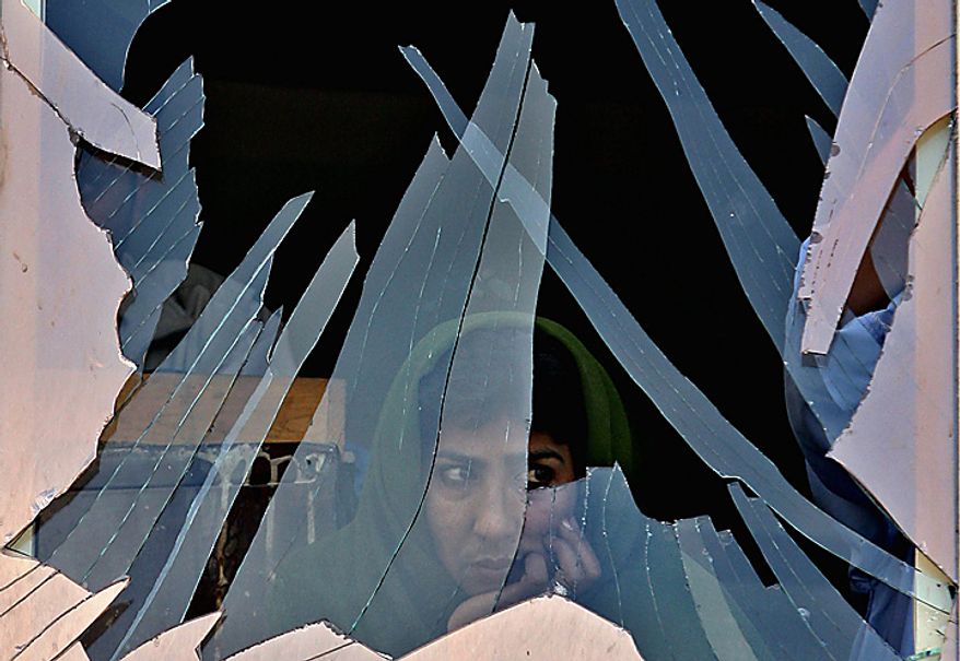 In this Tuesday, July 4, 2006 file picture, a woman looks out through a destroyed window after a bomb exploded in Kabul, Afghanistan in front of a cinema near the presidential palace, wounding at least four people, police said. (AP Photo/Rodrigo Abd, File)