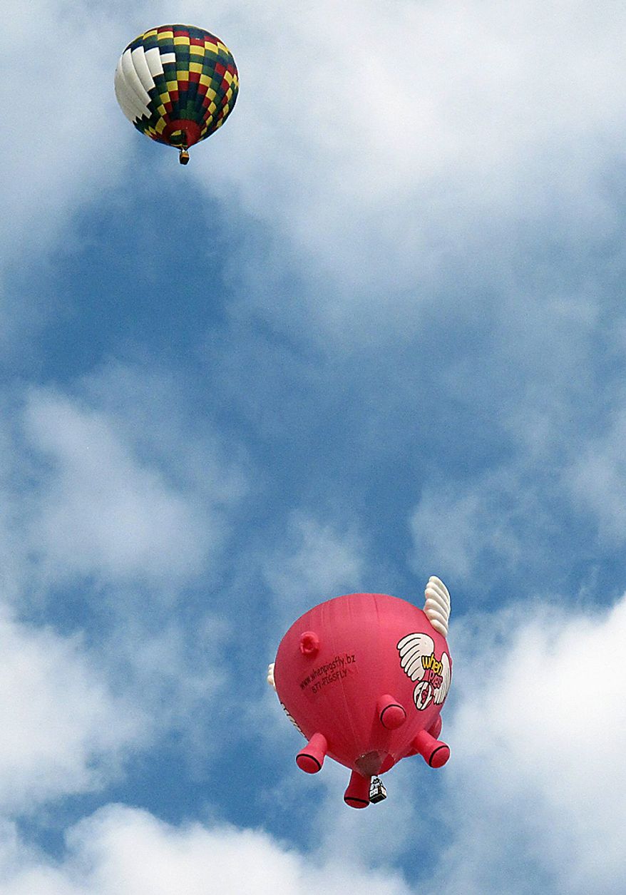 Hot air balloons, including a flying pig, float over Albuquerque, N.M., on the third day of the Albuquerque International Balloon Fiesta Monday, Oct. 4, 2010. (AP Photo/Tim Korte)