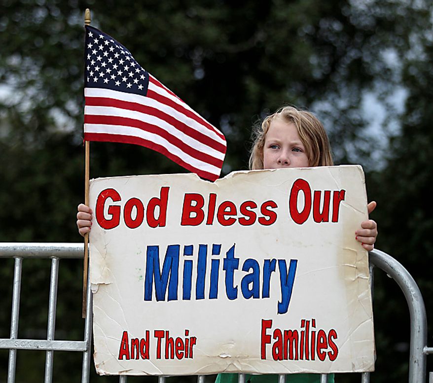 Audrey Low, 10, of Reston, Va., holds a sing as she watches from across the street as members of the Westboro Baptist Church dance on American Flags at Arlington National Cemetery in Arlington, Va., Tuesday, Oct. 5, 2010. (AP Photo/Carolyn Kaster)