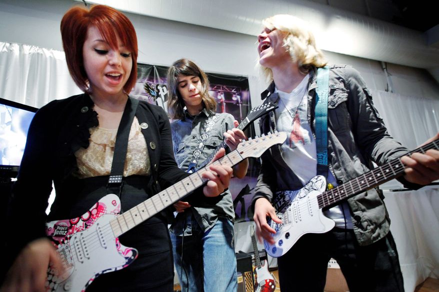 From left, Carly Kalafus, Ben Spremulli and Duran Visek perform on Paper Jamz guitars, which have been named to Time To Play's Holiday 2010 Most Wanted List. The musicians are part of the group Kicking Daisies. (Associated Press)