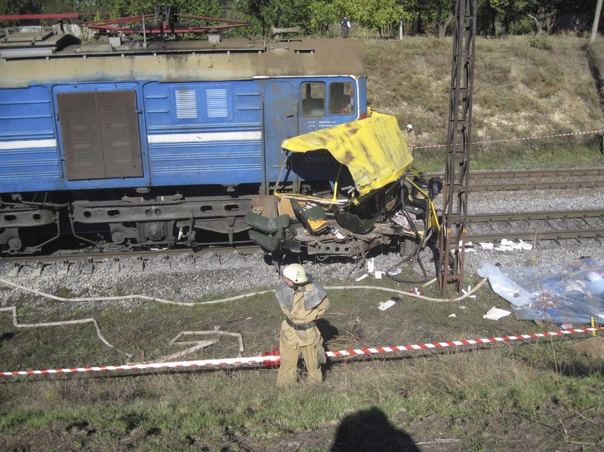 The remains of a bus lie next to a railway train at the site of an accident outside the town of Marhanets, Ukraine, on Tuesday, Oct. 12, 2010. The crowded passenger bus collided with the train in eastern Ukraine, killing at least 43 people and leaving 8 injured, police said. (AP Photo/Emergency Situations Ministry)

