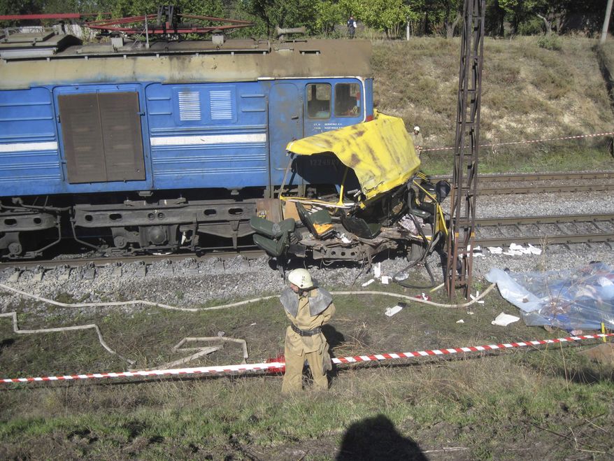 The remains of a bus lie next to a railway train at the site of an accident outside the town of Marhanets, Ukraine, on Tuesday, Oct. 12, 2010. The crowded passenger bus collided with the train in eastern Ukraine, killing at least 43 people and leaving 8 injured, police said. (AP Photo/Emergency Situations Ministry)