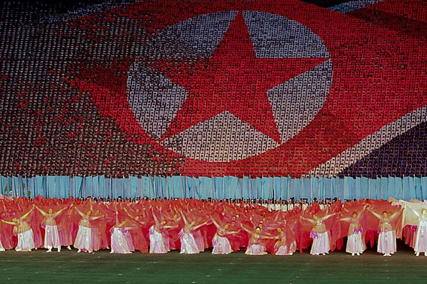 Performers dance in front of a depiction of the North Korean flag in Rungrado May Day Stadium during a ceremony commemorating the 65th anniversary of the Korea Worker's Party in Pyongyang, North Korea, on Saturday, Oct. 9, 2010. North Korean heir apparent Kim Jong Un stood at his father's right side today as they reviewed troops, tanks and missiles in a Pyongyang military parade. Photographer: Dieter Depypere/Bloomberg