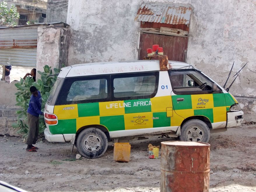 A boy hired to wash blood from an ambulance in Mogadishu, Somalia, won't be able to finish the job before its driver races off again to answer a call for help. (Associated Press)