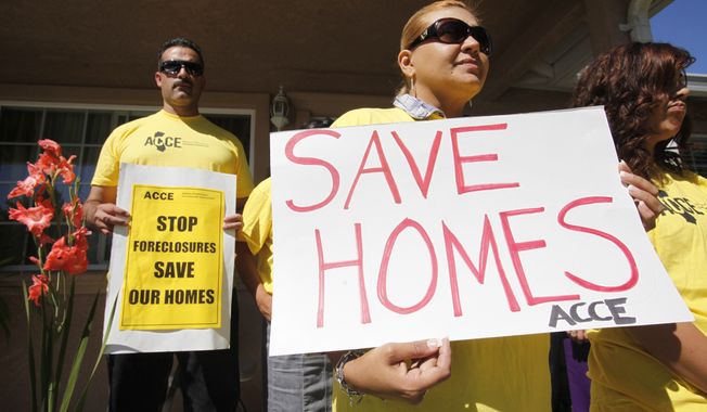 **FILE** In this photo from Sept. 24, 2010, supporter Marisa Salas (right) holds a sign during a foreclosure and eviction rally at the home of Carlos Moreno in Menlo Park, Calif. Moreno has owned his home since 2006, had his home under foreclosure since January 2010, and was served eviction notice in July 2010. His case is now pending with the bank. (Associated Press)