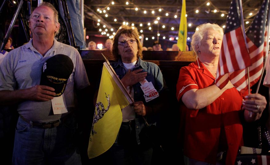 Patrick Mooney, his wife, Joan Mooney (center), and another woman sing the national anthem at the start of a Tea Party Express rally on Tuesday in Las Vegas. The Tea Party Express bus is on the second day of its 29-stop tour. It will cross 20 states before ending up in Concord, N.H., on Nov. 1. (Associated Press)