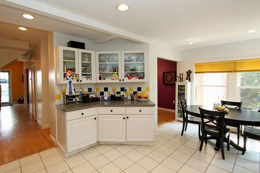 The kitchen features white cabinets, many with glass fronts, black appliances and a bright breakfast hear.