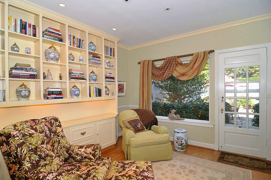 The library has a wall-length bookcase, hardwood flooring, a picture window facing the private patio and a glass door to the backyard.