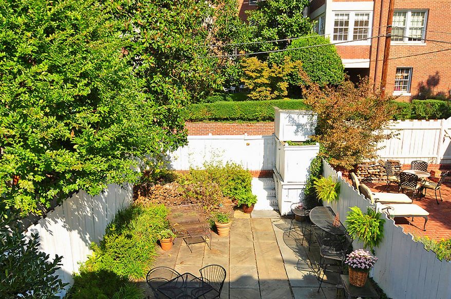 The fully fenced backyard has a stone-paved central patio surrounded by garden beds. There is plenty of space for gardening and entertaining.