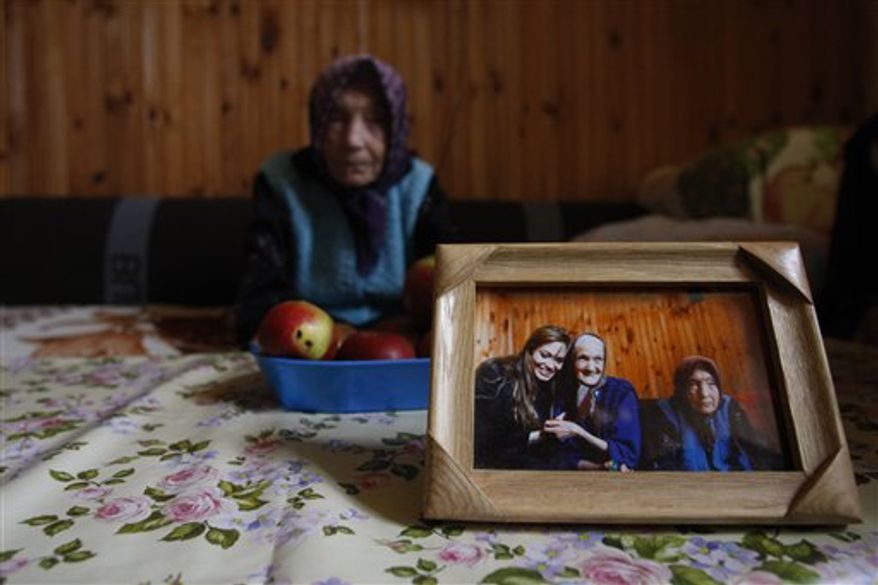Bosnian Serb refugee Borka Mandzo, 68,with her nephew Nemanja, 6, right, and niece Natasa,13, left, reflected in a wall mirror sits in her small room , inside the collective refugee center in the Bosnian town of Rogatica, 73 kms east of Sarajevo, Bosnia, Monday, Oct. 25, 2010. The Babic sisters were among other 15 refugees visited in April 2010 by UNHCR goodwill ambassador Angelina Jolie. Refugees in Rogatica belong to population of 117.000 who were not able to return their homes 15 years after Bosnian war. Refugees in this center after Jolies visit are convinced that things have started moving in terms of getting some donation leading the solving their house problem.(AP Photo/Amel Emric)