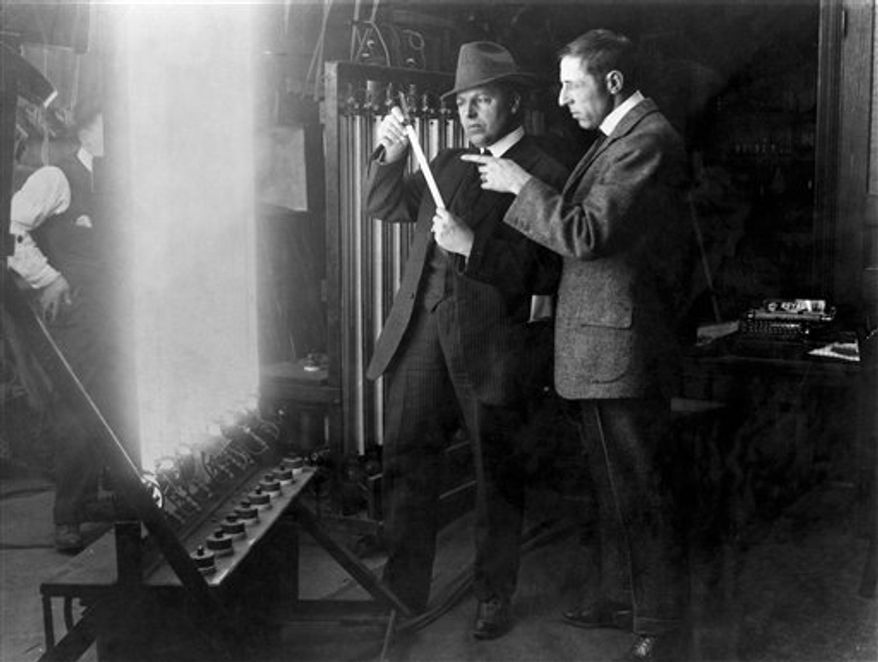 In this 1913 publicity image released by TCM, G.W "Billy" Bitzer, center, and D.W Griffith discuss early lighting techniques in a scene from seven-part documentary series "Moguls & Movie Stars: A History of Hollywood" beginning Monday, Nov. 1, 2010 on the Turner Classic Movie channel. (AP Photo/TCM)