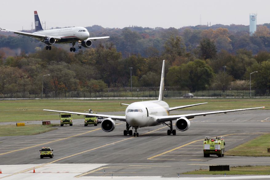 A jet lands near a United Parcel Service plane that is isolated on a runway at Philadelphia International Airport in Philadelphia, Friday, Oct. 29, 2010. Law enforcement officials are investigating reports of suspicious packages on cargo planes in Philadelphia and Newark, N.J. (AP Photo/Matt Rourke)