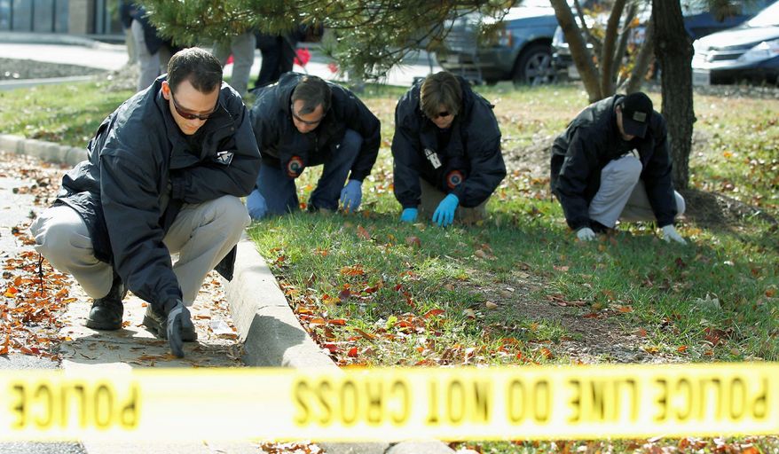 FBI investigators search for evidence near a U.S. Coast Guard recruiting office in Woodbridge, Va. Police in Northern Virginia said at least one shot was fired overnight at the recruiting office, damaging glass. (Associated Press)