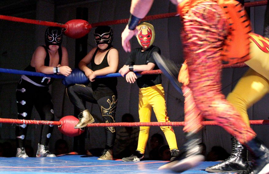 Children dressed up as wrestlers watch a match at a Lucha Libre Mexican wrestling night, part of Lucha Libre Internacional Gladiadores Unidos, at a family friendly venue in Phoenix. (Associated Press)