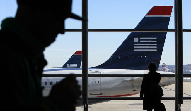 **FILE** Passengers walk past US Airways planes at Ronald Reagan Washington National Airport in suburban Washington on Dec. 27, 2009. (Associated Press)