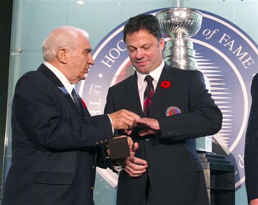Hockey Hall of Fame inductee Dino Ciccarelli, right, is given his ring by Hall Co-Chairman Jim Gregory at the Hall in Toronto on Monday Nov. 8, 2010. (AP Photo/The Canadian Press, Frank Gunn)
