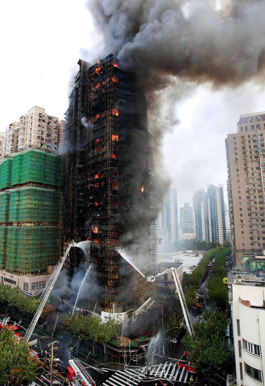 ASSOCIATED PRESS
Firefighters spray an apartment building on fire in Shanghai on Monday. At least 42 people died in the blaze.