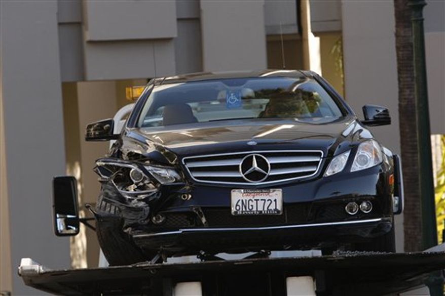 EDS: ADDS IDENTITY OF VICTIM -- A towtruck driver stands beside a damaged Mercedes E350 in which a woman, well-known Hollywood publicist Ronni Chasen, 64, was shot several times in the chest and killed on Tuesday, Nov 16, 2010 in Beverly Hills, Calif. A police statement says Chasen was shot several times at Sunset Boulevard and Whittier Drive. Her vehicle then crashed into a light pole. (AP Photo/Nick Ut)