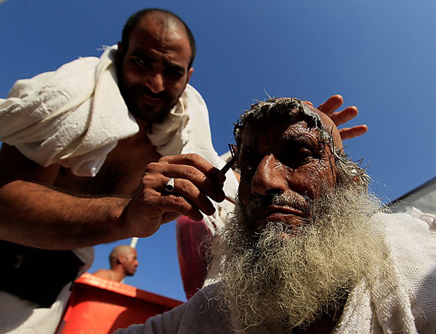 A Muslim pilgrim has his head shaved, after throwing pebbles at a stone pillar representing the devil, during the Hajj pilgrim in Mina near Mecca, Saudi Arabia, Tuesday, Nov. 16, 2010. The last stage of the annual Hajj pilgrimage, the symbolic stoning of the devil, began on Friday. The first day of stoning also marks the start of the Islamic holiday of Eid al-Adha, or feast of sacrifice, when Muslims around the world slaughter sheep and cattle in remembrance of Abraham's near-sacrifice of his son. (AP Photo/Hassan Ammar)