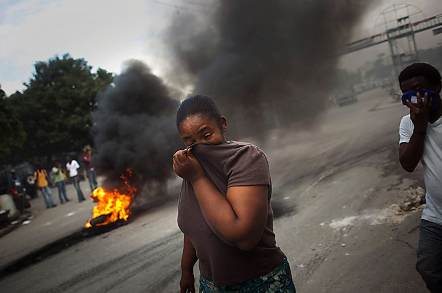 A woman covers her face from the smoke of burning tires set up by demonstrators in Port-au-Prince, Haiti, Monday, Nov. 15, 2010. Students in the capital protested burning tires and throwing stones at police, following demonstrations that began early Monday in the northern city of Cap-Haitien where protesters attacked with stones a U.N. base of Nepalese peacekeepers, whom they hold responsible for the outbreak of cholera that has killed around 1,000 people in three weeks. (AP Photo/Emilio Morenatti)