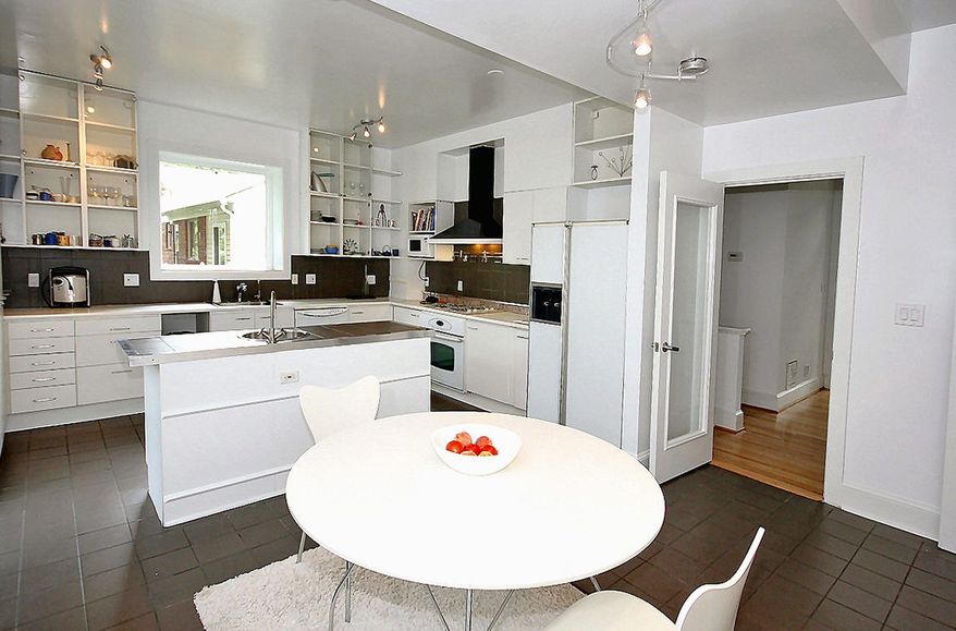 The kitchen has dark gray tile flooring with a matching backsplash and white open and glass-front cabinets.
