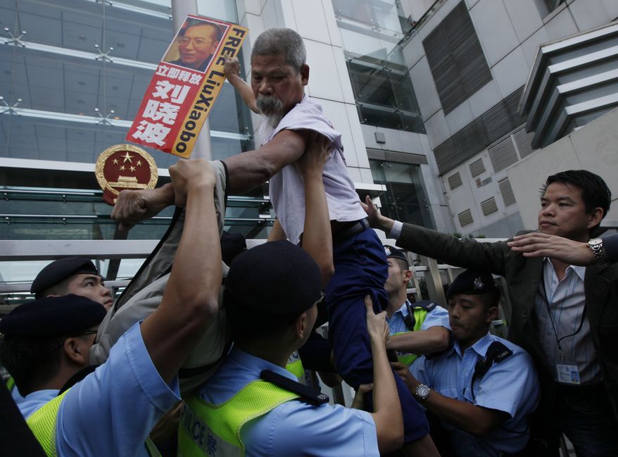 A pro-democracy protester holding the picture of the jailed Chinese dissident Liu Xiaobo, tries to climb across the police line during a demonstration at the China Liaison Office in Hong Kong Thursday, Nov. 11, 2010. The Norwegian Nobel Committee hopes Chinese authorities will allow the wife or some other close relative of imprisoned Nobel Peace Prize winner Liu Xiaobo to travel to Oslo and accept the award on his behalf. (AP Photo/Kin Cheung)