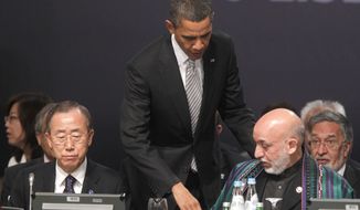 U.S. President Barack Obama, center, walks over to greet Afghanistan President Hamid Karzai, right, seated, during the start of the Afghanistan Opening Session at NATO Summit in Lisbon, Portugal, on Saturday, Nov. 20, 2010. Also, sitting at left is United Nations Secretary-General, Ban Ki-moon. (AP Photo/Pablo Martinez Monsivais)