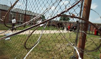 THE WASHINGTON TIMES
Razor wire wraps around a fence at Oak Hill Academy, which was closed by a D.C. Council mandate. 
