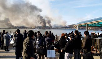 BRINK OF WAR: South Koreans watch smoke rising from South Korea&#39;s Yeonpyeong Island near the border with North Korea on Tuesday. The North fired artillery barrages onto the island. South Korea returned fire and launched fighter jets. (Associated Press)