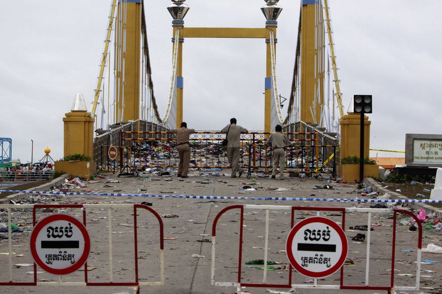 Cambodian police officers stand behind a barricade at the site where people stampeded during a water festival in Phnom Penh, Cambodia, Tuesday, Nov. 23, 2010. Thousands of people stampeded during the festival in the Cambodian capital, leaving more than 300 dead and scores injured in what the prime minister called the country's biggest tragedy since the 1970s reign of terror by the Khmer Rouge. (AP Photo/Heng Sinith)