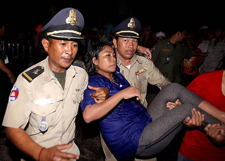 An injured visitor is carried by Cambodian police and another visitor after a stampede onto a bridge at an accident site during the last day of celebrations of the water festival in Phnom Penh, Cambodia, Monday, Nov. 22, 2010. Thousands of people celebrating a water festival on a small island in a Cambodian river stampeded Monday evening, killing many people, a hospital official said. Hundreds more were hurt as the crowd panicked and pushed over the bridge to the mainland. (AP Photo/Heng Sinith)