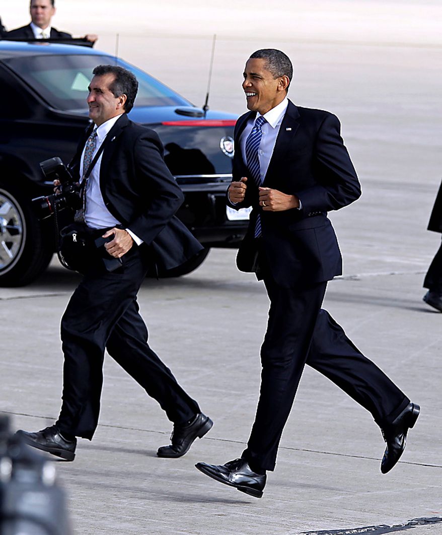 President Barack Obama jogs across the tarmac to greet supporters after he arrived on Air Force One at Grissom Air Reserve Base in Peru, Ind., Tuesday, Nov. 23, 2010. White House photographer Pete Souza is at left. (AP Photo/Michael Conroy)