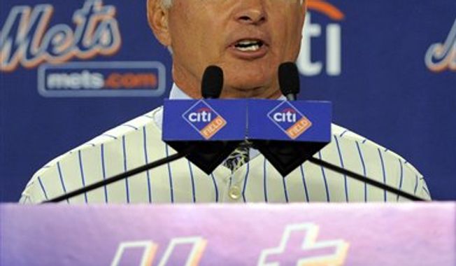 New York Mets General Manager Sandy Alderson, left, assists newly named Mets manager Terry Collins with a jersey during a news conference at Citi Field in New York, Tuesday, Nov. 23, 2010. (AP Photo/Stephen Chernin)