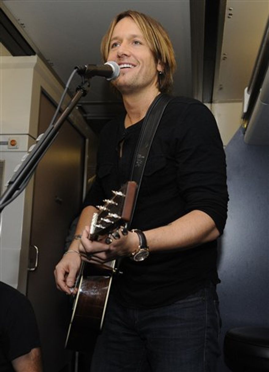 FILE - A Nov. 16, 2010 file photo shows Keith Urban performing a free concert for winners of a contest conducted by his website, aboard an Amtrak train traveling from Philadelphia to New York. Urban is trying to make his fans and his family happy this summer. The multi-platinum country star is hitting the road June 16 on a 44-city arena tour in the U.S. with a schedule that gives him time to be with his wife, actress Nicole Kidman, and their 2-year-old daughter, Sunday Rose.(AP Photo/Henny Ray Abrams, File)