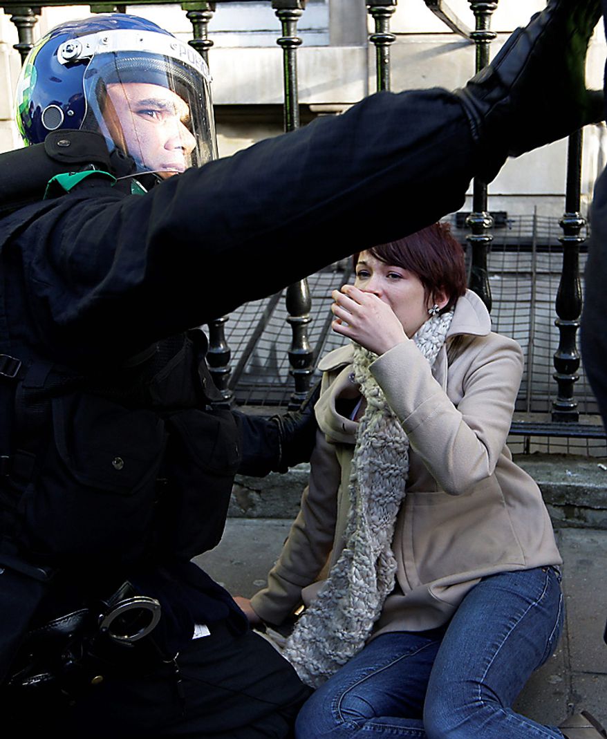 An injured protester is treated by police medic as thousands of students protest against tuition fees at Whitehall in London, Wednesday, Nov. 24, 2010. (AP Photo/Sang Tan)