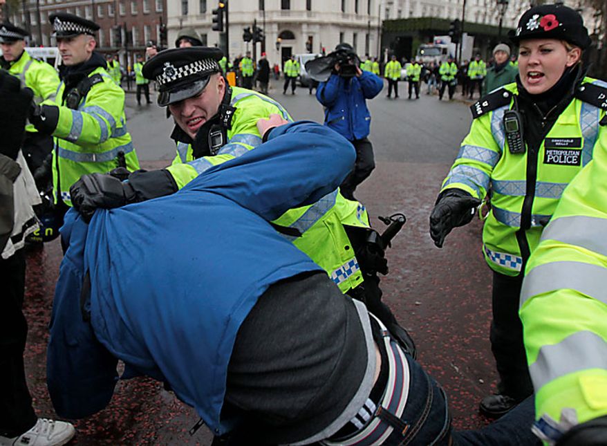 A British police officer scuffles with a protester during a march by a group of students outside Buckingham Palace, protesting against tuition fees increases in central London, Tuesday, Nov. 30, 2010. Thousands of British students protested Wednesday against government plans to triple university tuition fees. (AP Photo/Lefteris Pitarakis)